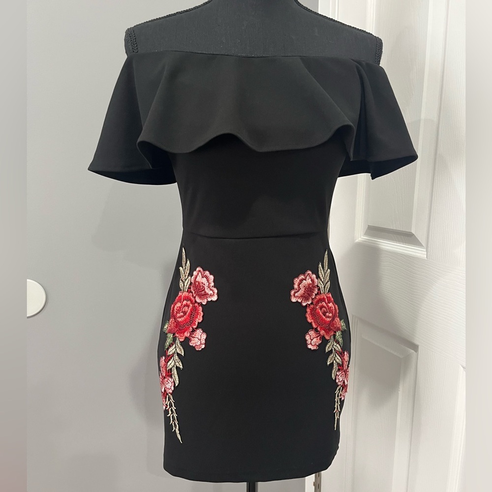Haute Rogue black off the shoulder mini dress with floral appliqué.